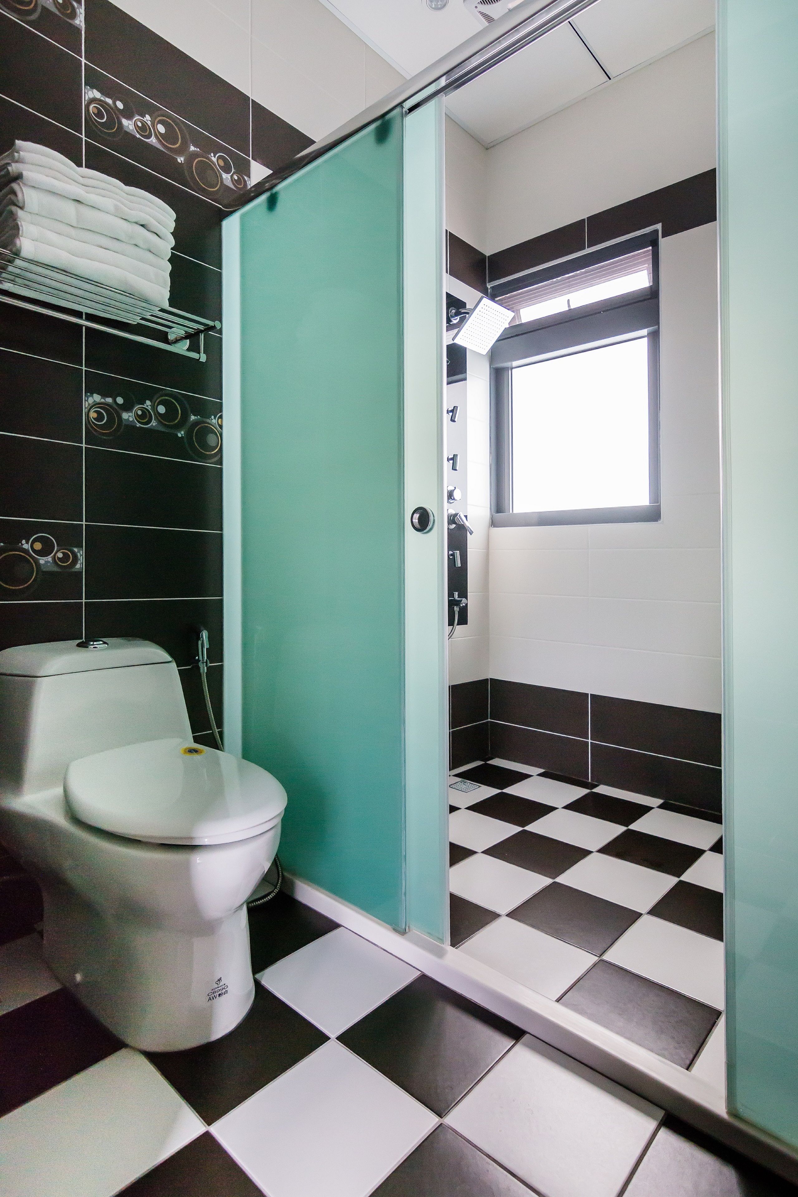 A bathroom with a toilet, a shower area, and a checkered floor.