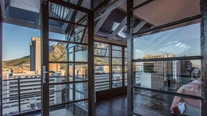 Un intérieur moderne doté de grandes fenêtres offrant une vue sur le paysage urbain et les montagnes.