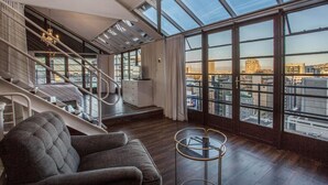 Un salon moderne avec un escalier, de grandes fenêtres et une vue sur la ville.
