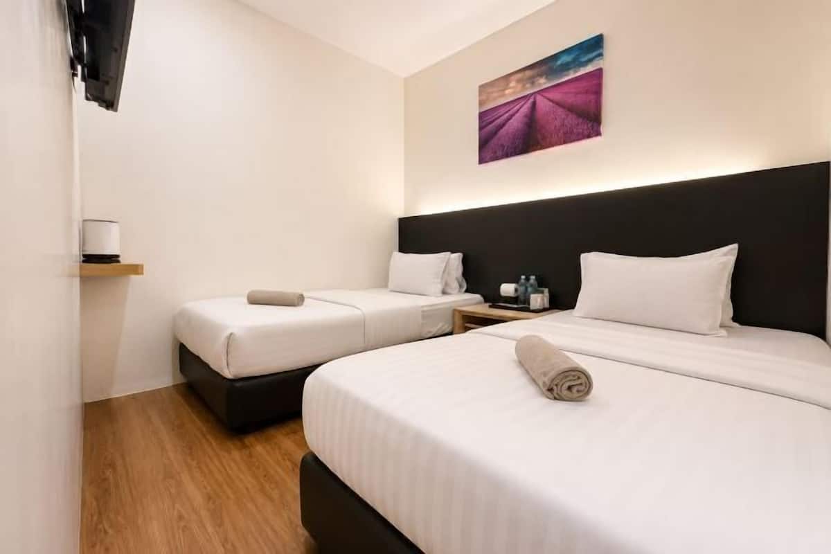 Ein Hotelzimmer mit zwei Betten, einem Kopfteil, einem Nachttisch, einem Wand-Fernseher und einem Gemälde.