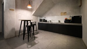 A compact kitchen with a dining area, a hanging light fixture, and a sign indicating a guest pantry. - Monaco Boutique Hotel Kampung Air (Kota Kinabalu)