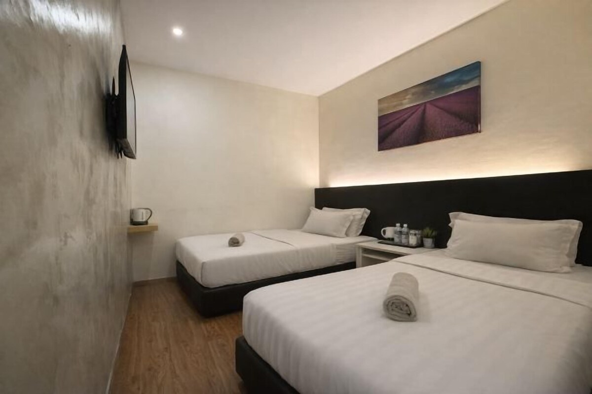 Een hotelkamer met twee bedden, een schilderij aan de muur, een klein kastje met toiletartikelen en een houten vloer.