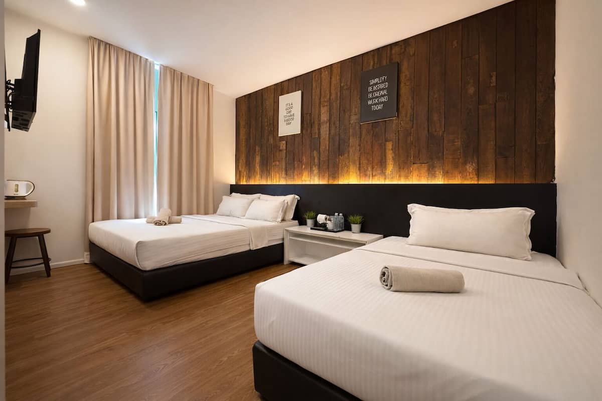 Ein Hotelzimmer mit zwei Betten, einer Wand mit Holzverkleidung, einem Flachbildfernseher und einem Nachttisch mit Lampe.