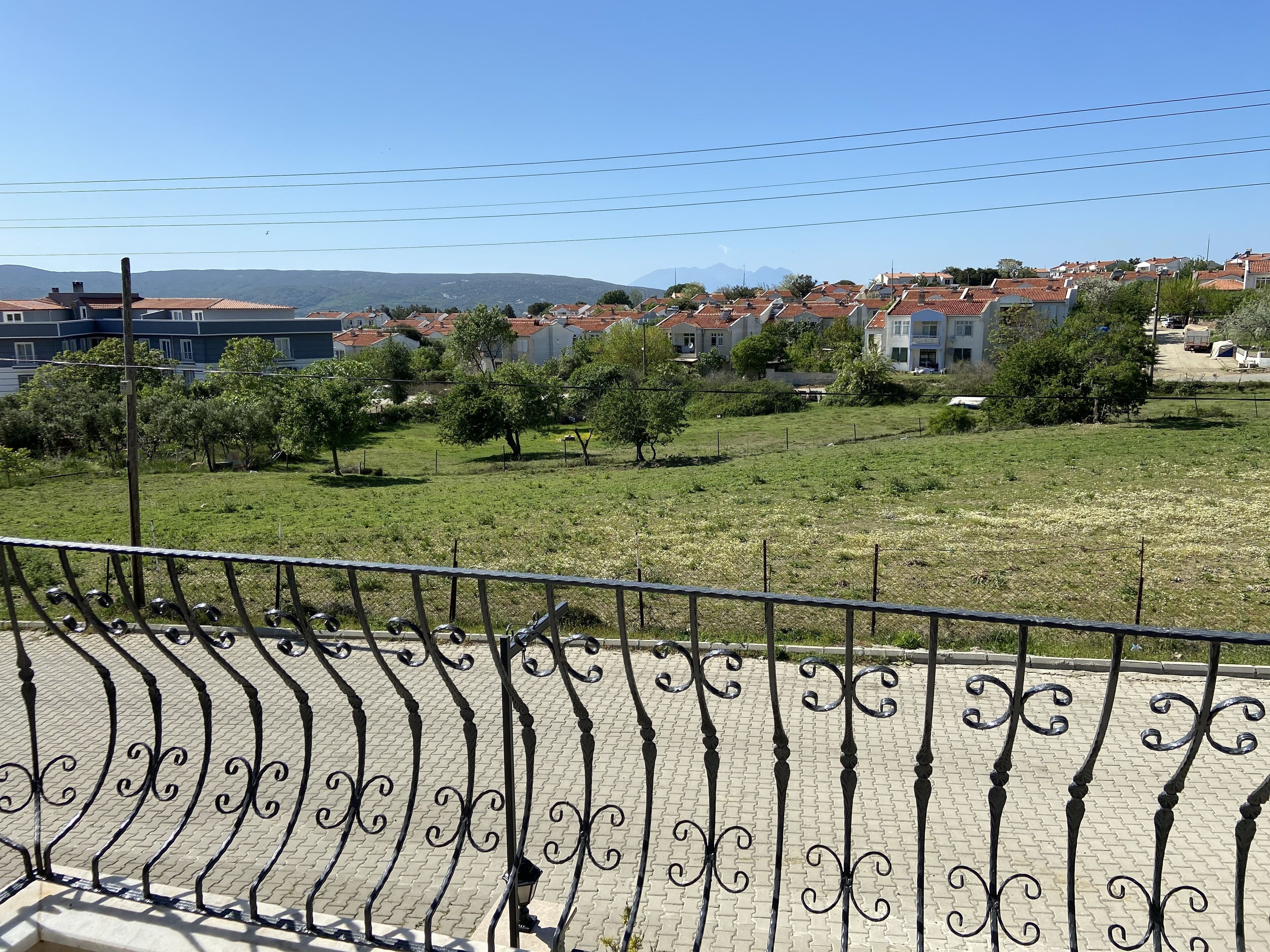 Zona residencial con casas, árboles y un camino pavimentado con barandillas de metal decorativas.