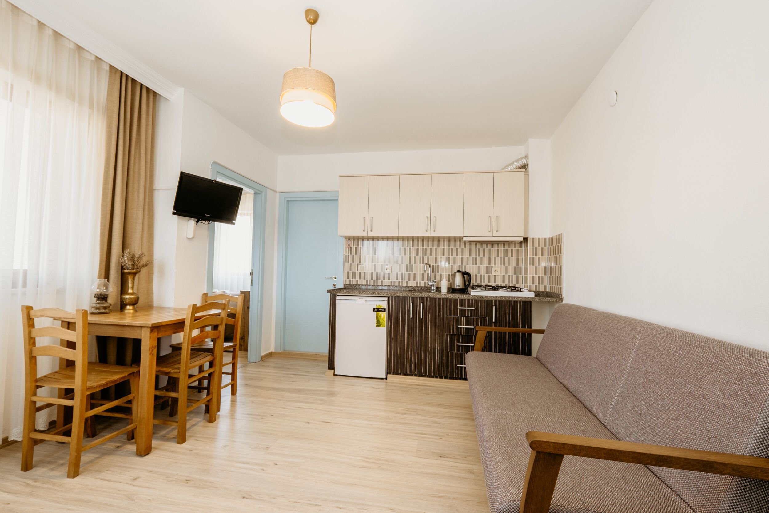 A compact living space with a dining area, kitchenette, and a sofa.