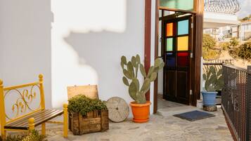 Um pátio com um banco, plantas em vasos e uma porta com painéis de vidro coloridos.