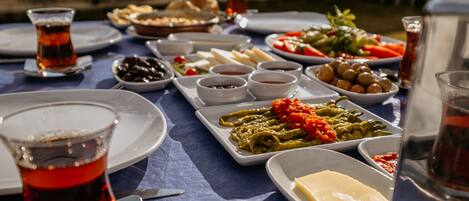 Una mesa dispuesta con diversos platos, incluyendo aceitunas, queso y verduras, con vistas a edificios al fondo.