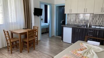 Un espacio habitable compacto con zona de comedor, kitchenette y cama.