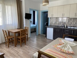 Un espacio habitable compacto con zona de comedor, kitchenette y cama.