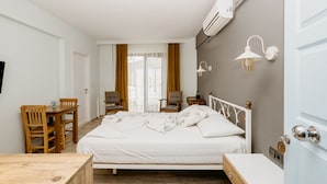 A bedroom with a bed, a wooden desk, chairs, and a nightstand. - Azra Apart & Otel (Gökçeada)