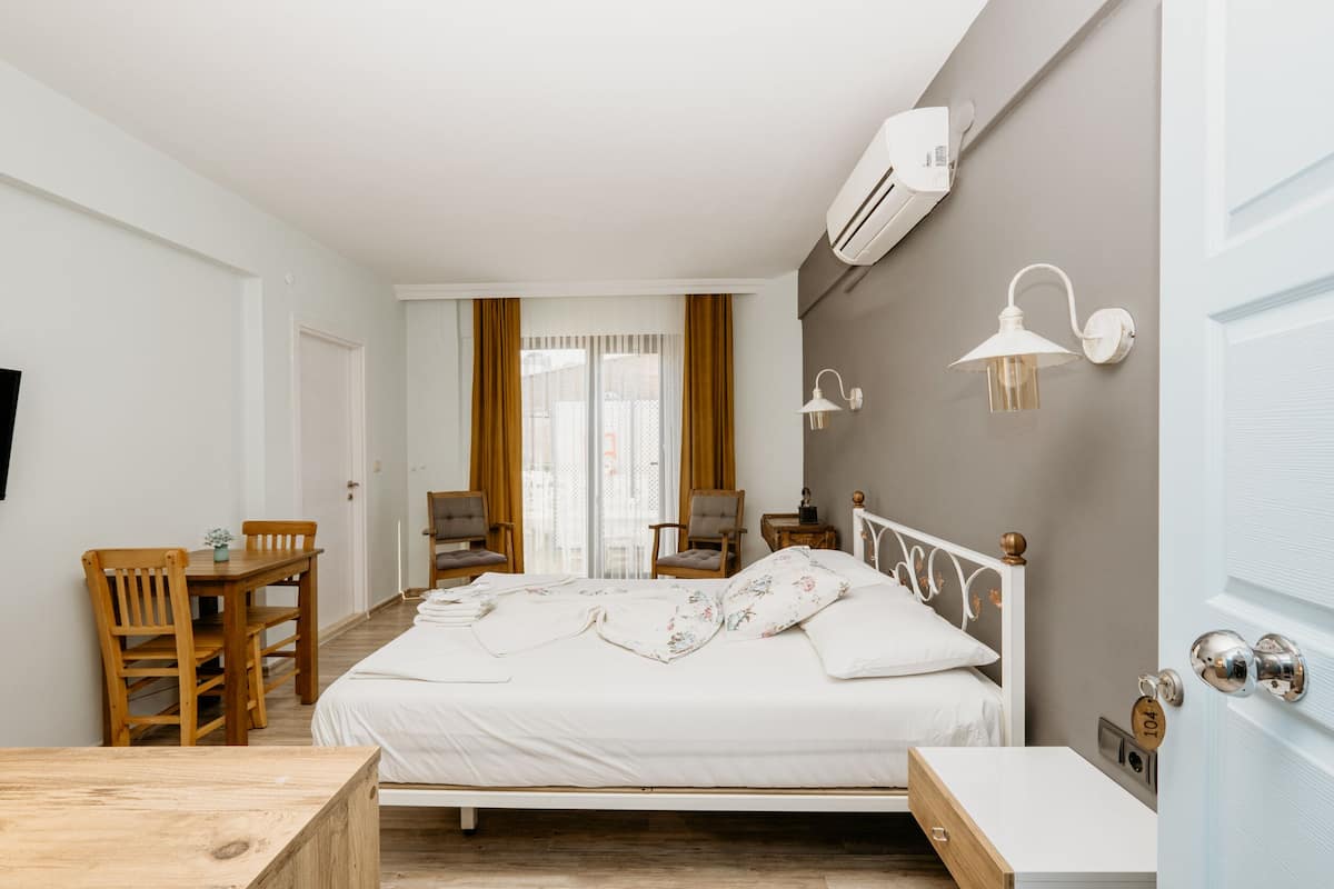 A bedroom with a bed, a wooden desk, chairs, and a nightstand.