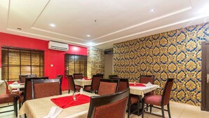 A dining area with tables set for two, red walls, and patterned wallpaper. - Royal Terrace Hotel & Towers (Lagos)