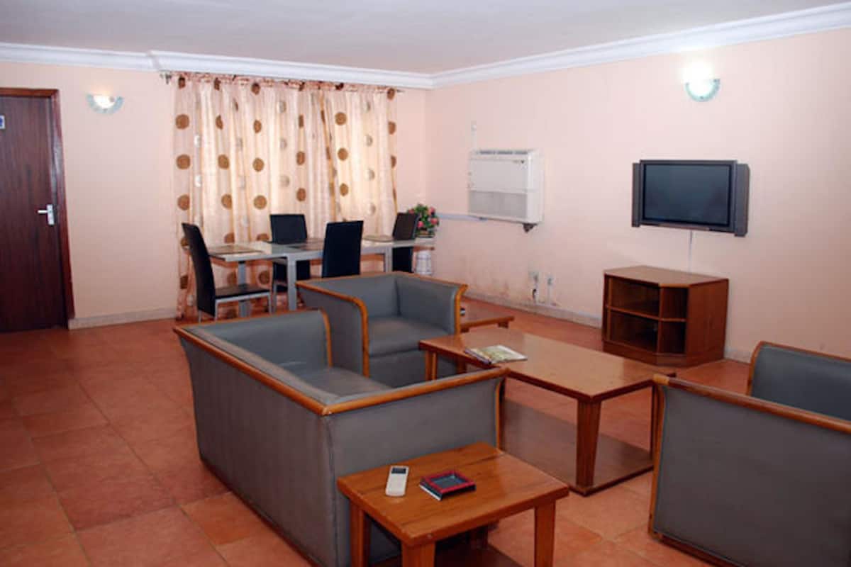 Een woonkamer met banken, een salontafel, een televisie en een bureau met computers.