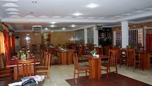 Ein geräumiges Restaurant mit mehreren Holztischen und Stühlen, Deckenleuchten und Klimaanlagen.