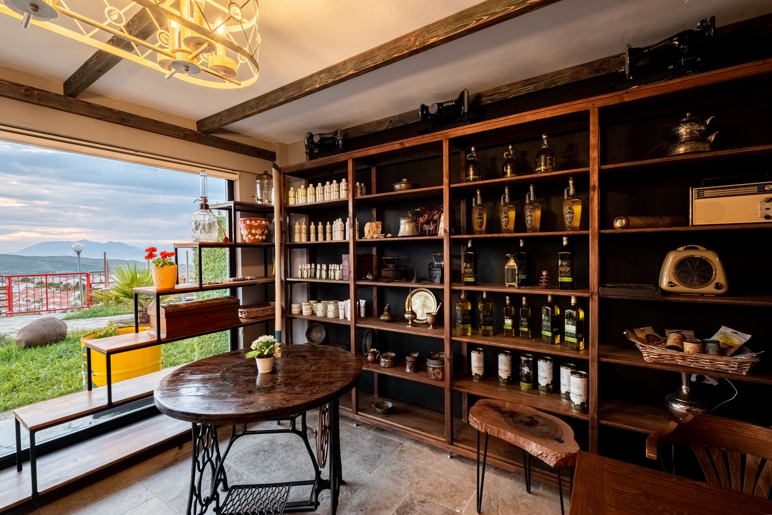 Una habitación acogedora con una amplia estantería de madera llena de botellas y frascos, una mesa redonda de madera y vistas al exterior.