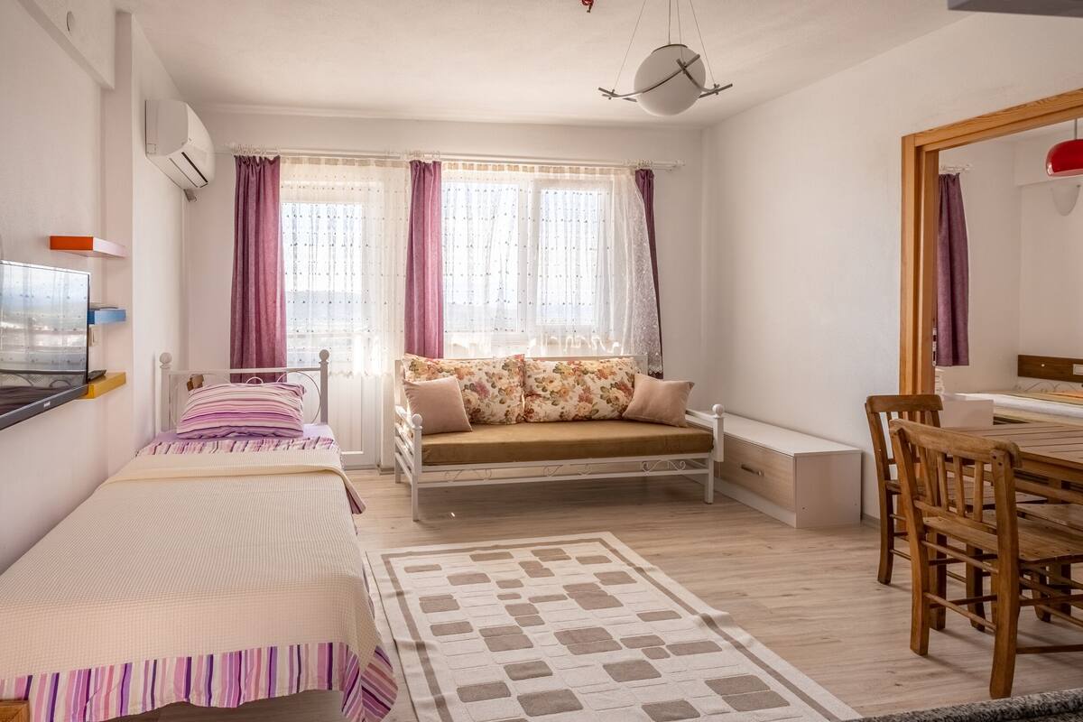 Ein Schlafzimmer mit zwei Betten, einer Couch, einem Esstisch und einem Spiegel.