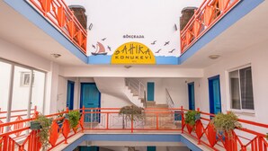 Ein mehrgeschossiges Gebäude mit einem zentralen Atrium, roten Geländern und einem Segelboot-Wandbild an der Decke.