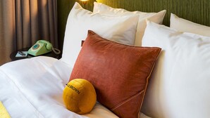 A neatly made bed with white linens, a brown pillow, and a yellow accent pillow. - Max Brown Hotel 7th District, part of Sircle Collection (Vienna)