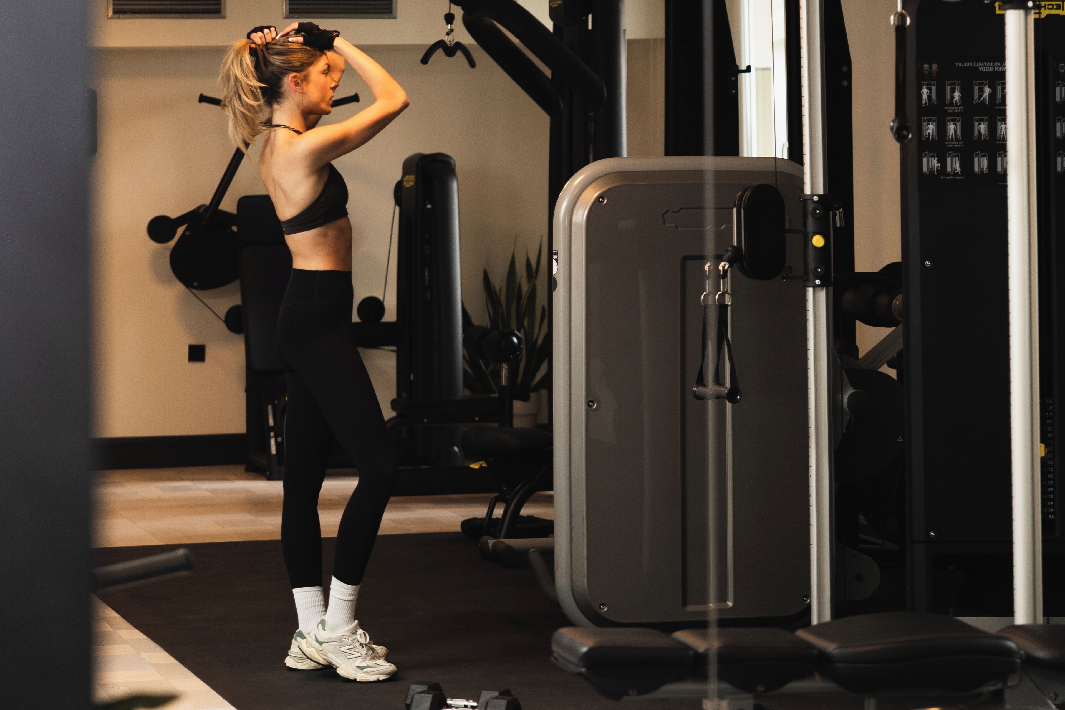 Uma academia com equipamentos de exercícios, um banco de musculação e um saco de pancadas fixado na parede.