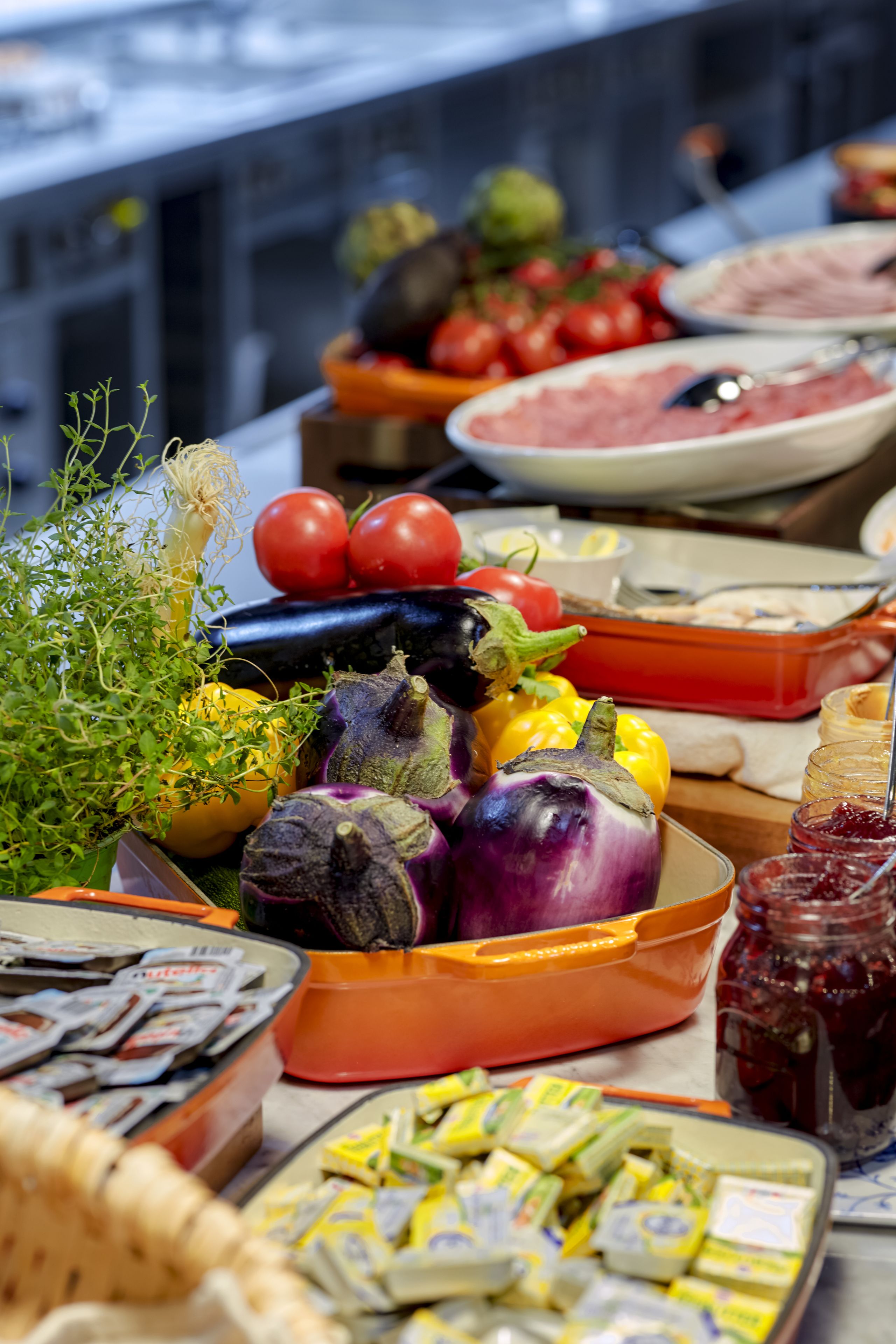 Uma mesa de buffet com diversos alimentos, incluindo vegetais, queijos e acompanhamentos.