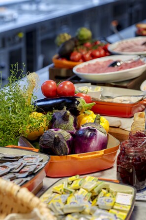 A buffet table with various food items including vegetables, cheeses, and condiments. - Max Brown Hotel 7th District, part of Sircle Collection (Vienna)