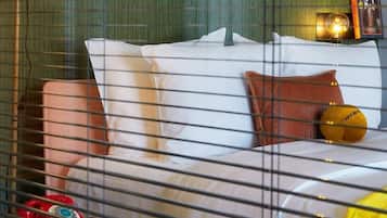 Una habitación de hotel con una cama, almohadas, un teléfono rojo y una lámpara.