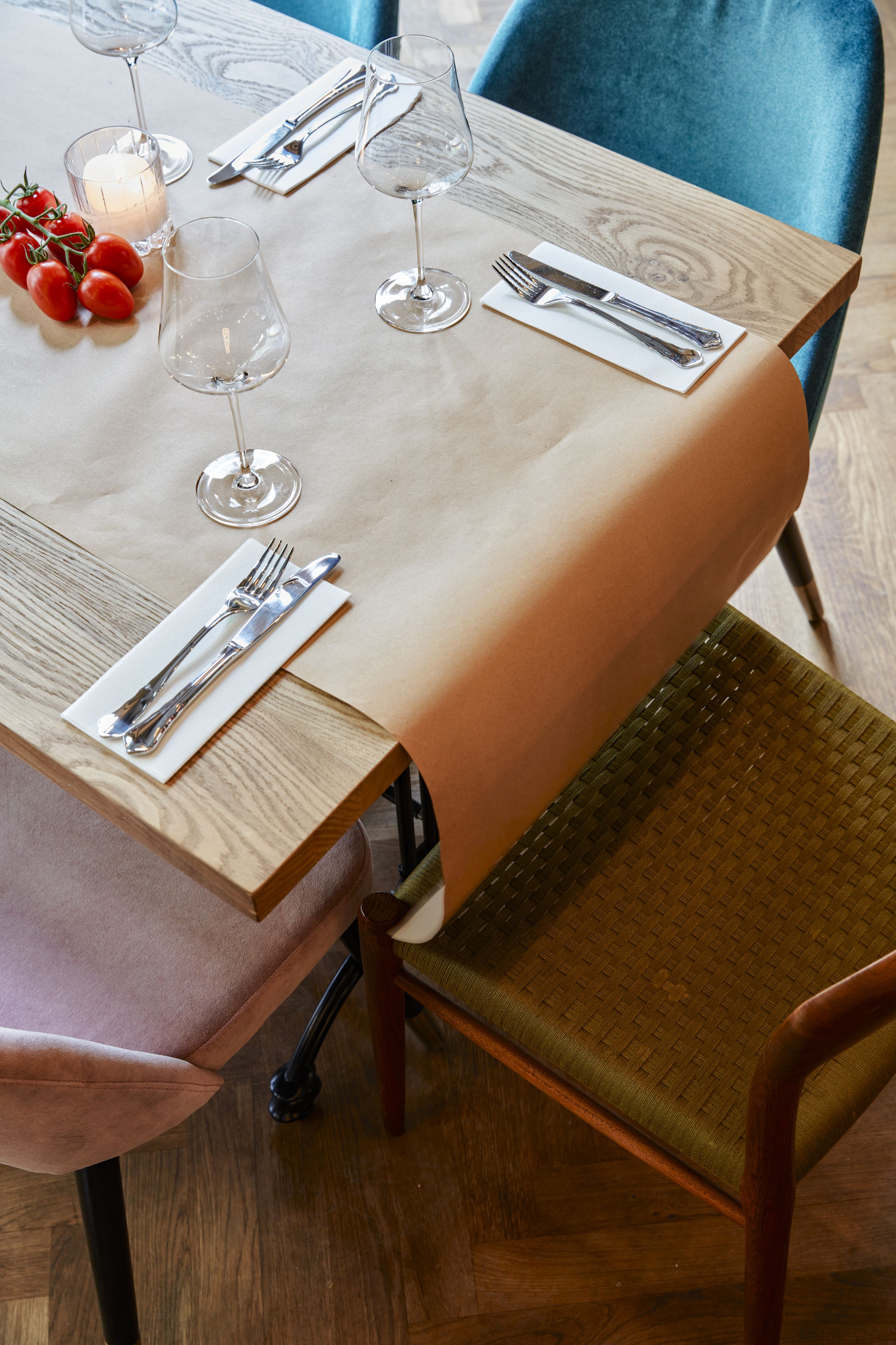 Mesa de jantar posta com uma vela, copos de vinho e talheres.
