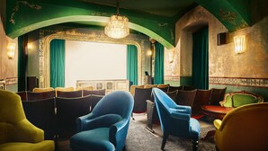 A vintage theater interior with rows of plush armchairs, a large ornate mirror, and a chandelier. - Max Brown Hotel 7th District, part of Sircle Collection (Vienna)