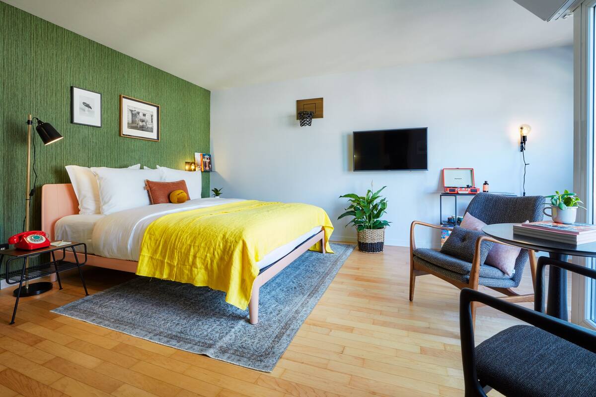 A modern bedroom with a bed, bedside table, lamp, and a TV.
