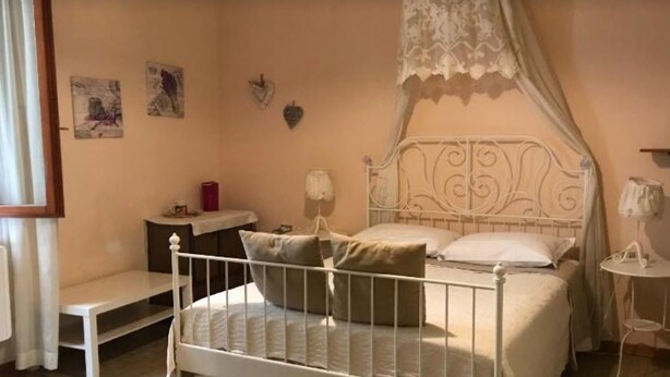 Une chambre à coucher comprenant un lit, une table de chevet, une lampe et une petite étagère ornée d’objets décoratifs.
