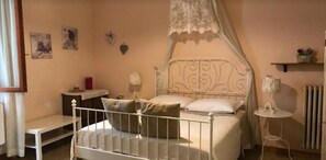 Un dormitorio con cama, mesita de noche, lámpara y una pequeña estantería con adornos.