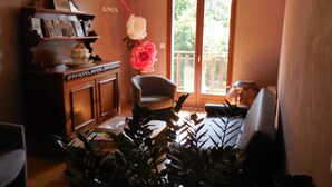 A living room with a wooden cabinet, a chair, and a potted plant. - Hôtel restaurant Marinet (Valserhône)