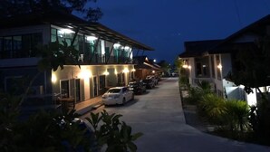 A hotel with a covered outdoor area, multiple cars parked in front, and a pathway leading to the entrance. - Veerada Boutique Home (Chaiya)
