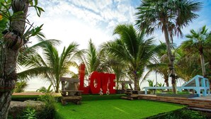 A tropical garden with a red 'LOVE' sign, palm trees, and a small blue structure. - Veerada Boutique Home (Chaiya)