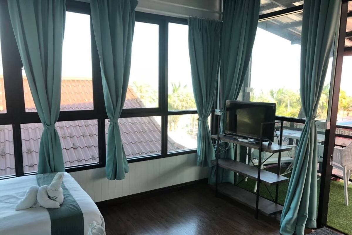 A hotel room with a bed, a TV, a desk, and a view of the outdoors.