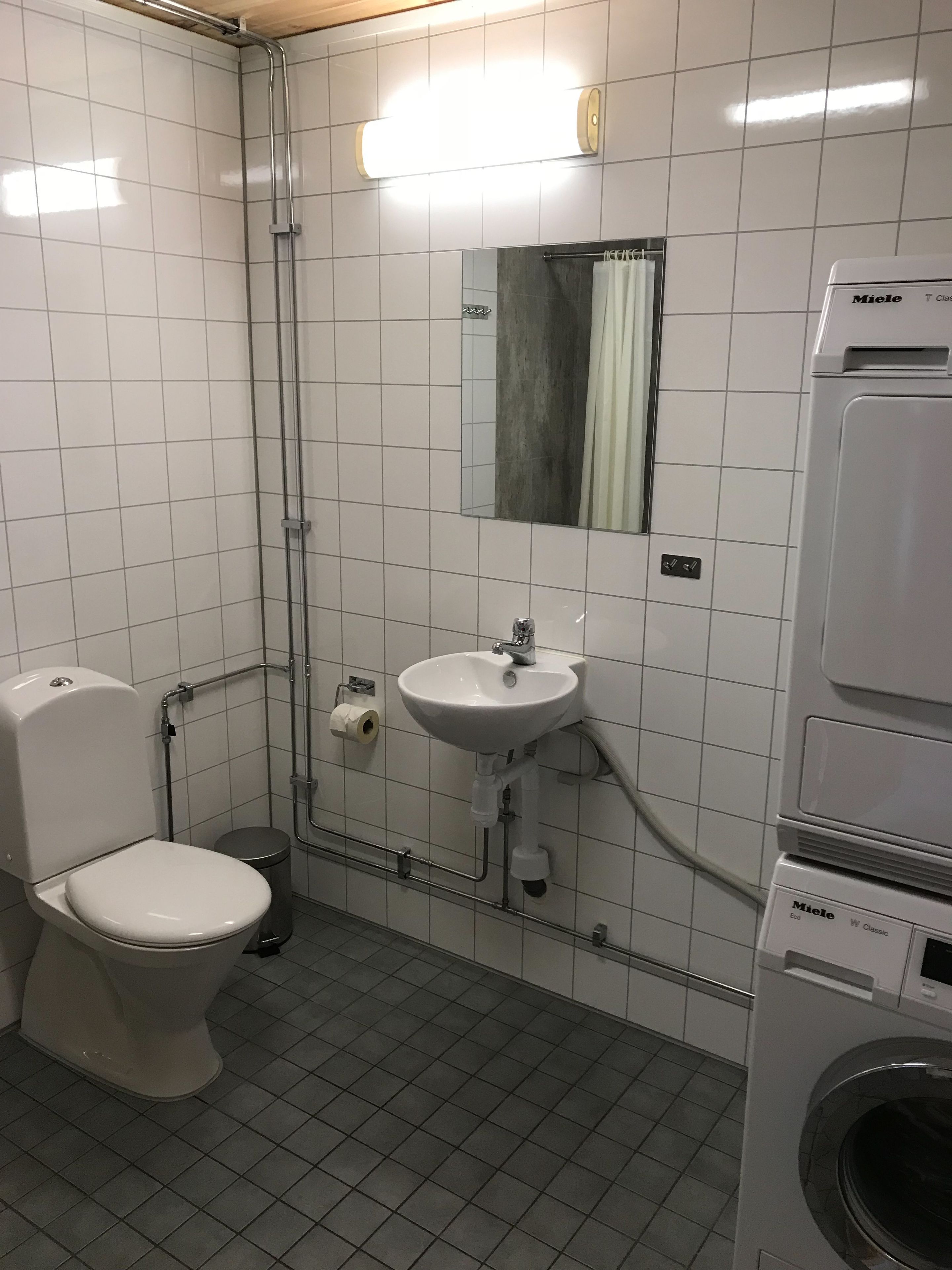 A bathroom with a toilet, sink, and washing machine.