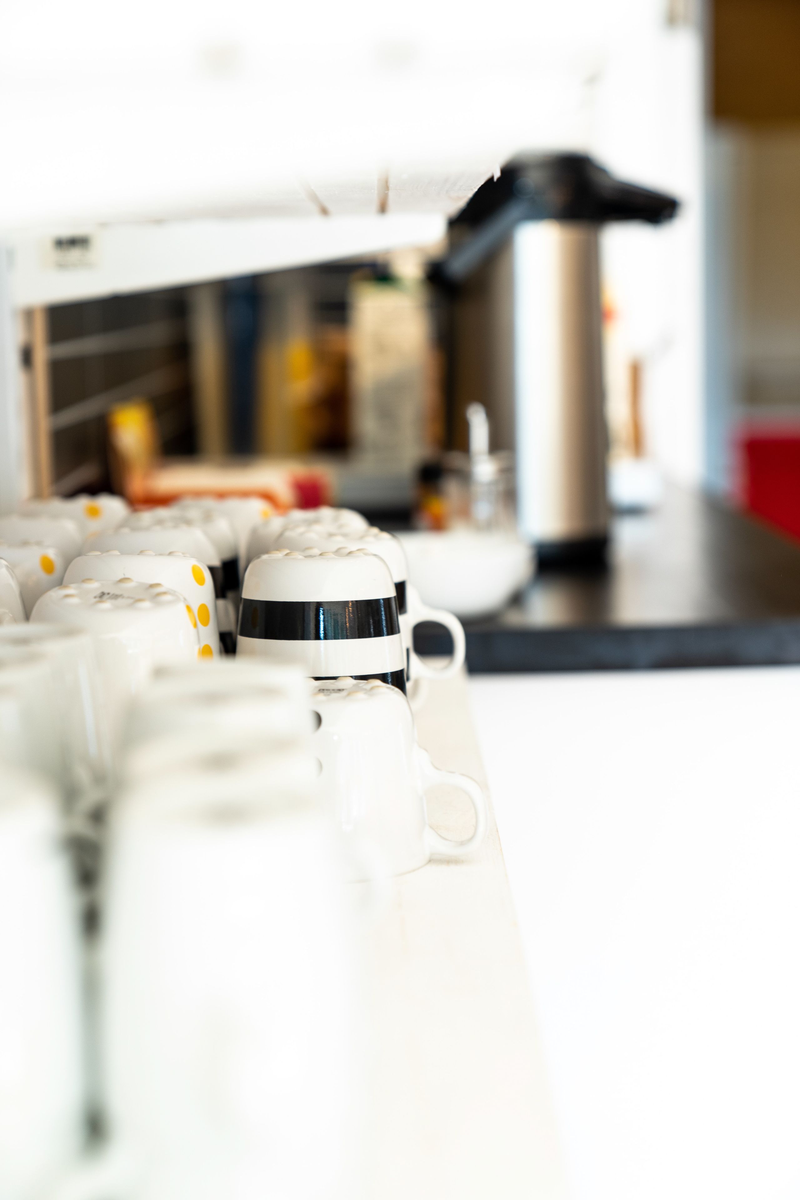 A kitchen with white cabinets, a stainless steel pot, and a coffee machine.