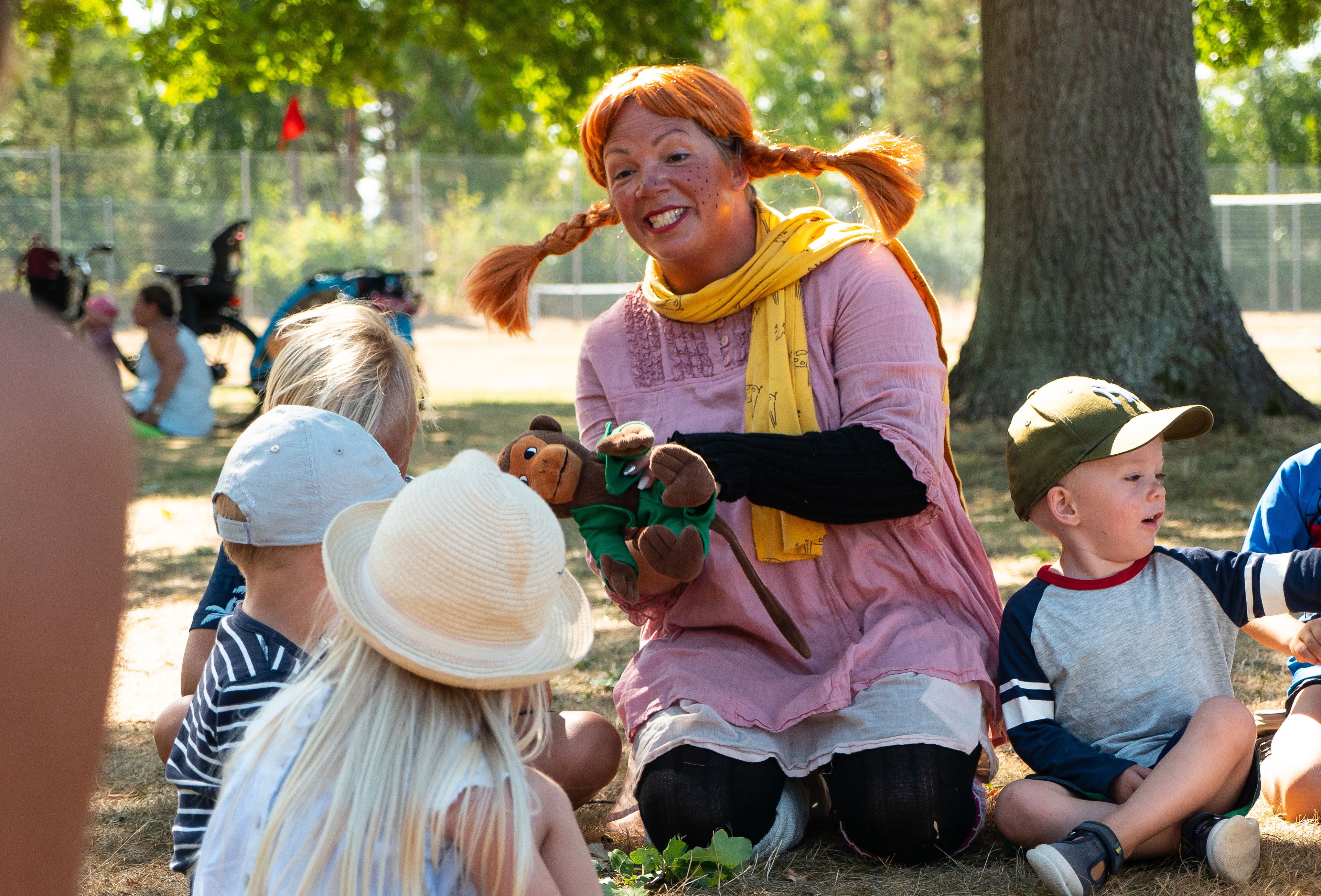 En grupp människor sitter på gräset utomhus.
