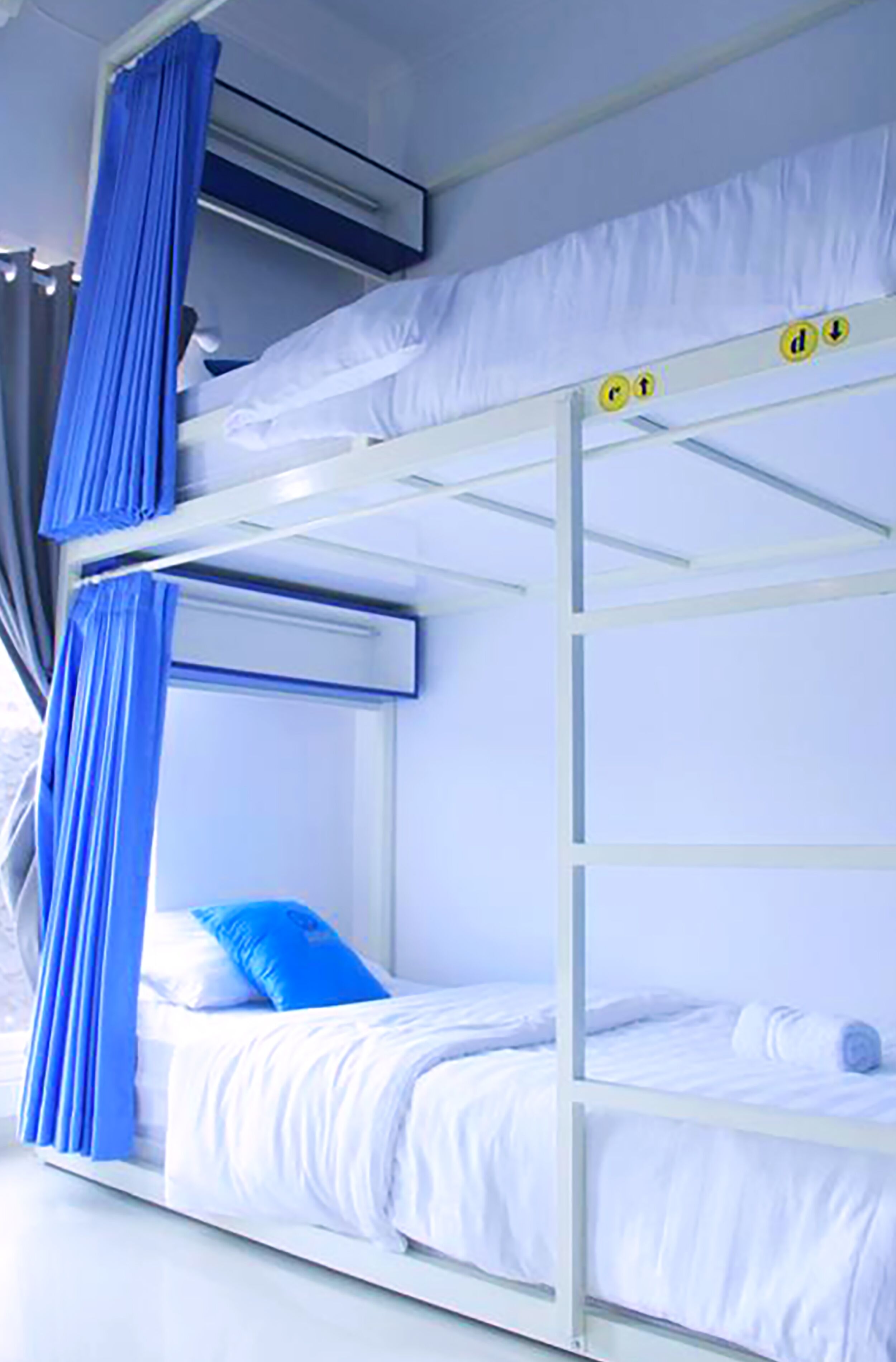 Ein Stockbett mit weißer Bettwäsche und blauen Vorhängen.