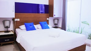 Habitación de hotel con una cama grande, dos mesitas de noche, un cabecero moderno y vistas al exterior.