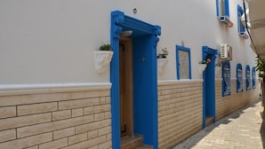 A narrow street with a building featuring blue doors and white walls. - Denizkizi Motel (Ayvacik)