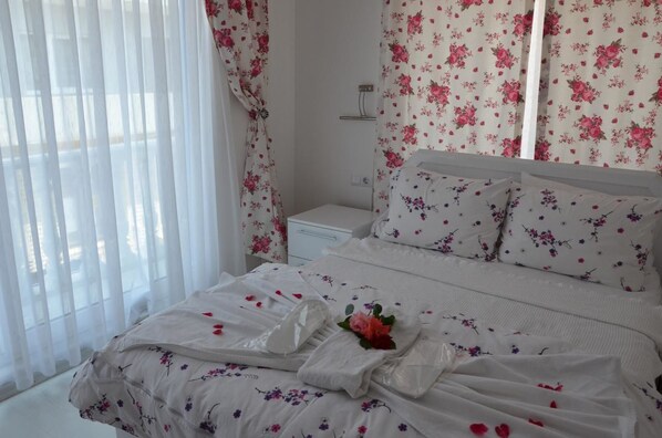 Uma cama bem arrumada com roupa de cama florida, uma mesa de cabeceira e cortinas estampadas com flores.