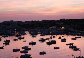 Un puerto deportivo lleno de barcos al atardecer.