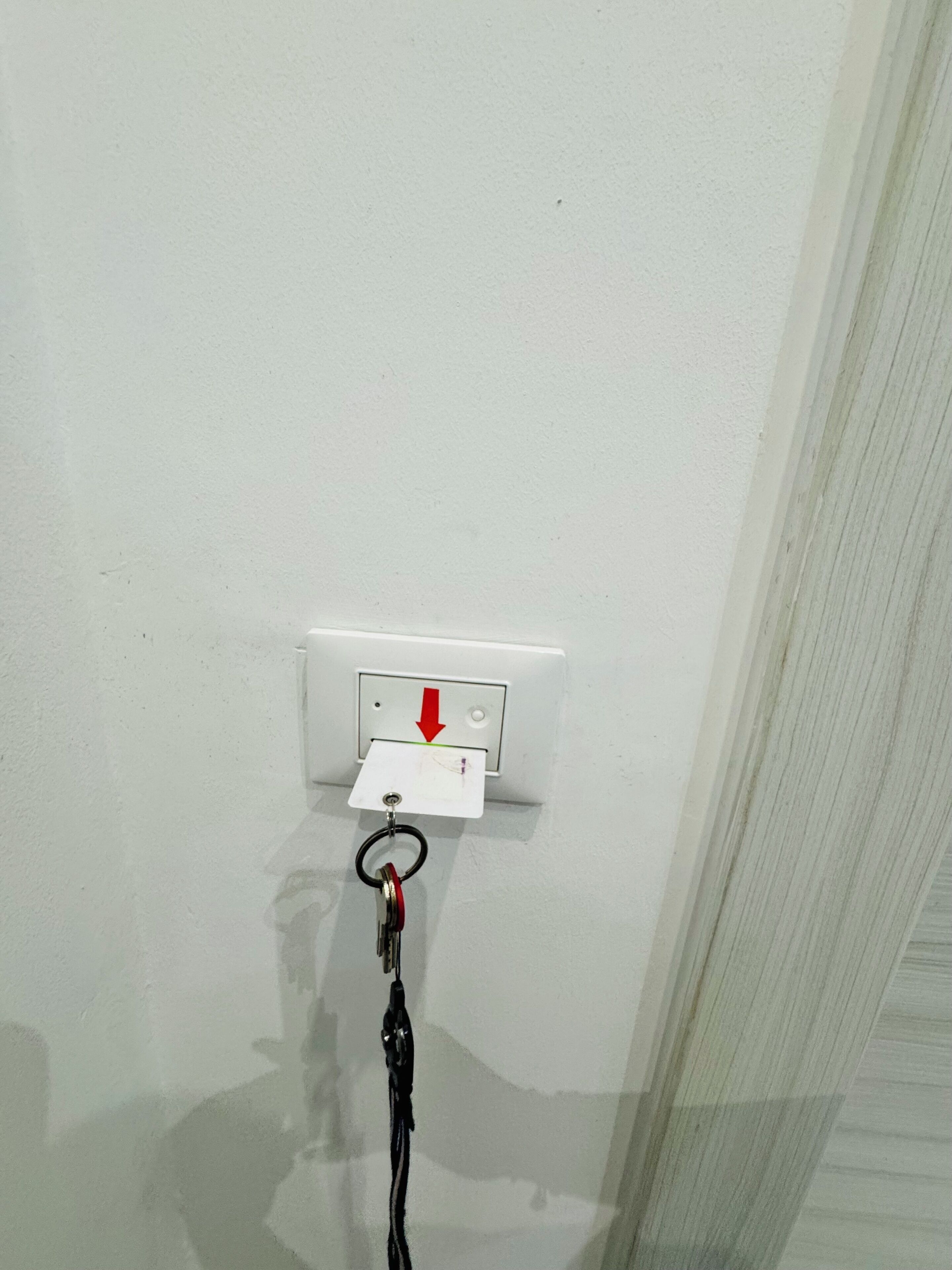 Un muro bianco con una presa di corrente e un portachiavi appeso.