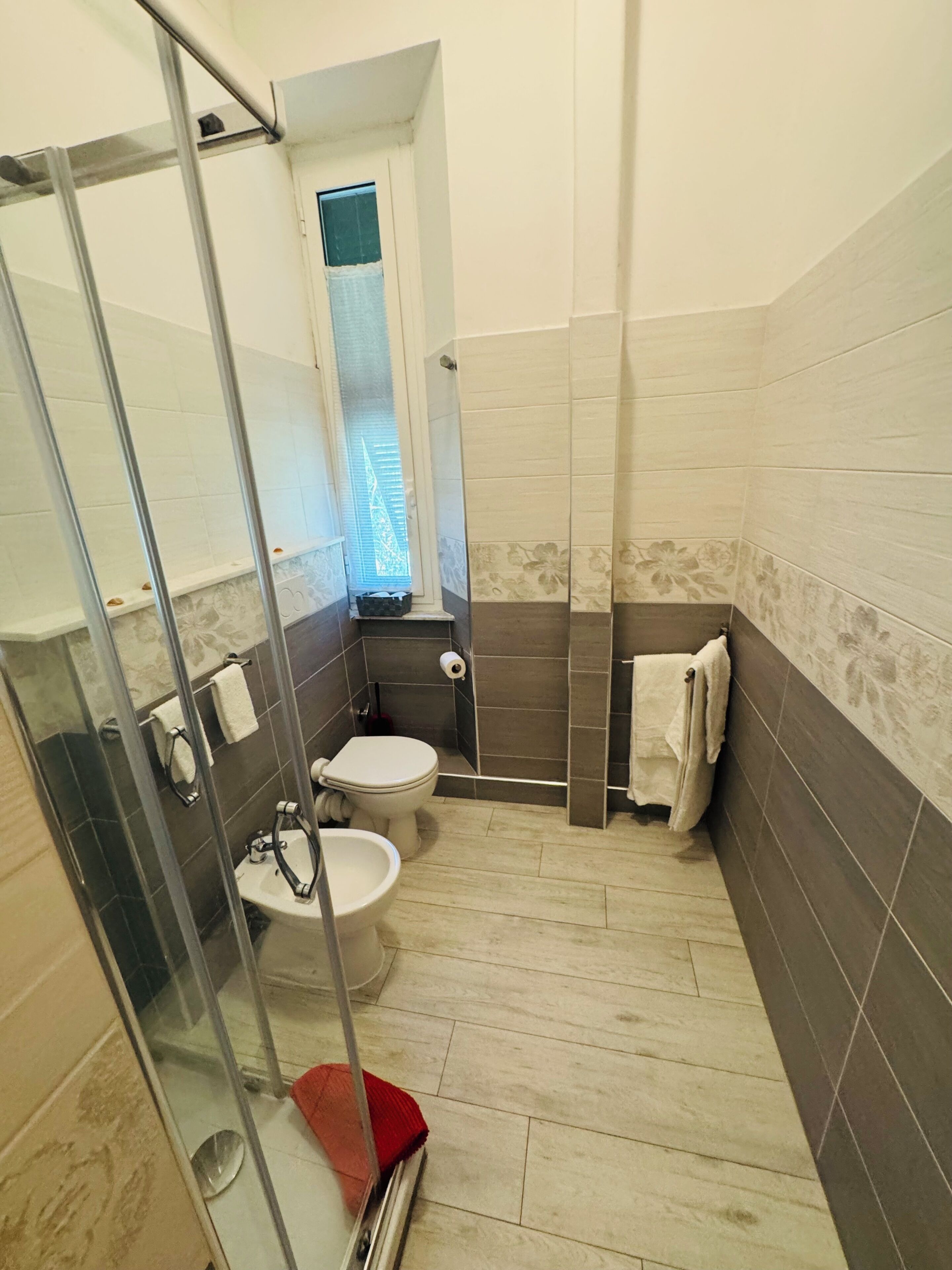 Een badkamer met een douchecabine van glas, een toilet en een bidet.