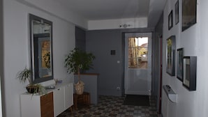 A hallway with a checkered floor, a white cabinet with a mirror, a potted plant, and a door leading to another room. - Chambre d'hôte Calme et Volupté (Maxilly-sur-Saône)