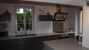 A modern kitchen with a large window, built-in appliances, and a checkered floor. - Chambre d'hôte Calme et Volupté (Maxilly-sur-Saône)