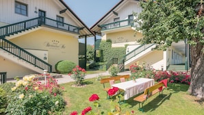 Un hotel con un jardín que incluye bancos y mesas, una escalera y un letrero que indica que es un hotel-apartamento.