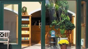 Exterior del Hotel Birnbacher Aparthotel, con entrada despejada, una banca afuera y macetas con plantas en primer plano.