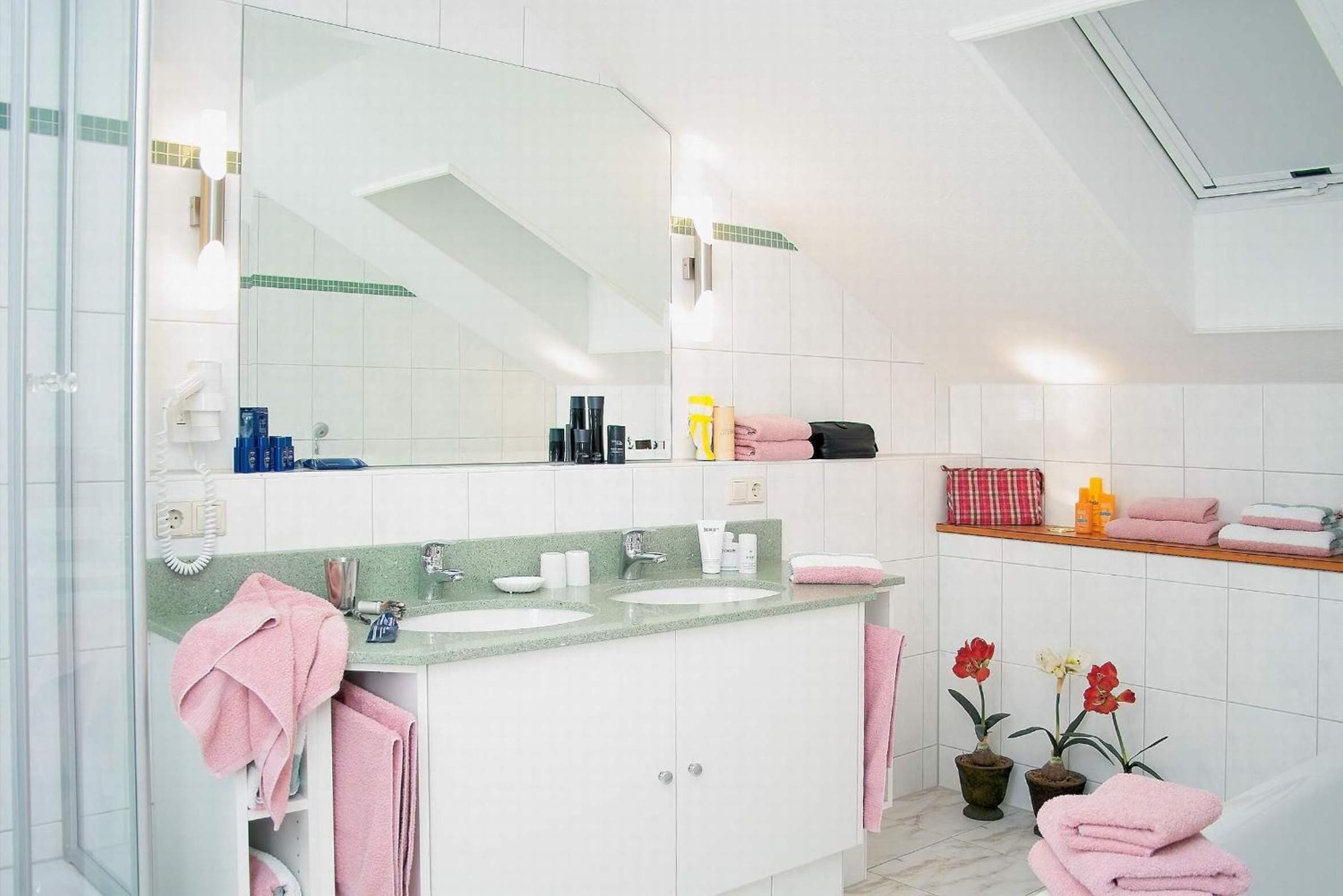 Een moderne badkamer met twee wastafels, een grote spiegel en een douchehoek.